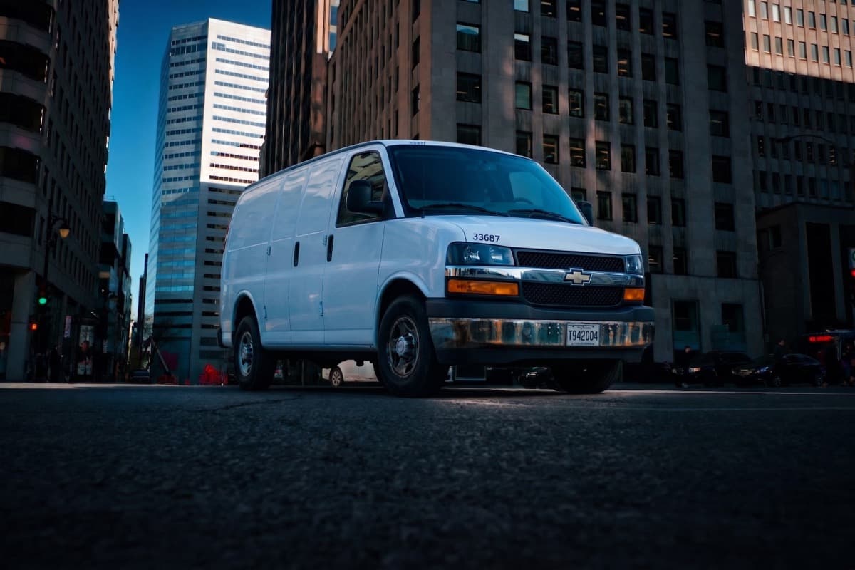 A white cargo delivery van parked on a downtown city street, representing last-mile retail delivery and logistics that drive revenue and customer retention.