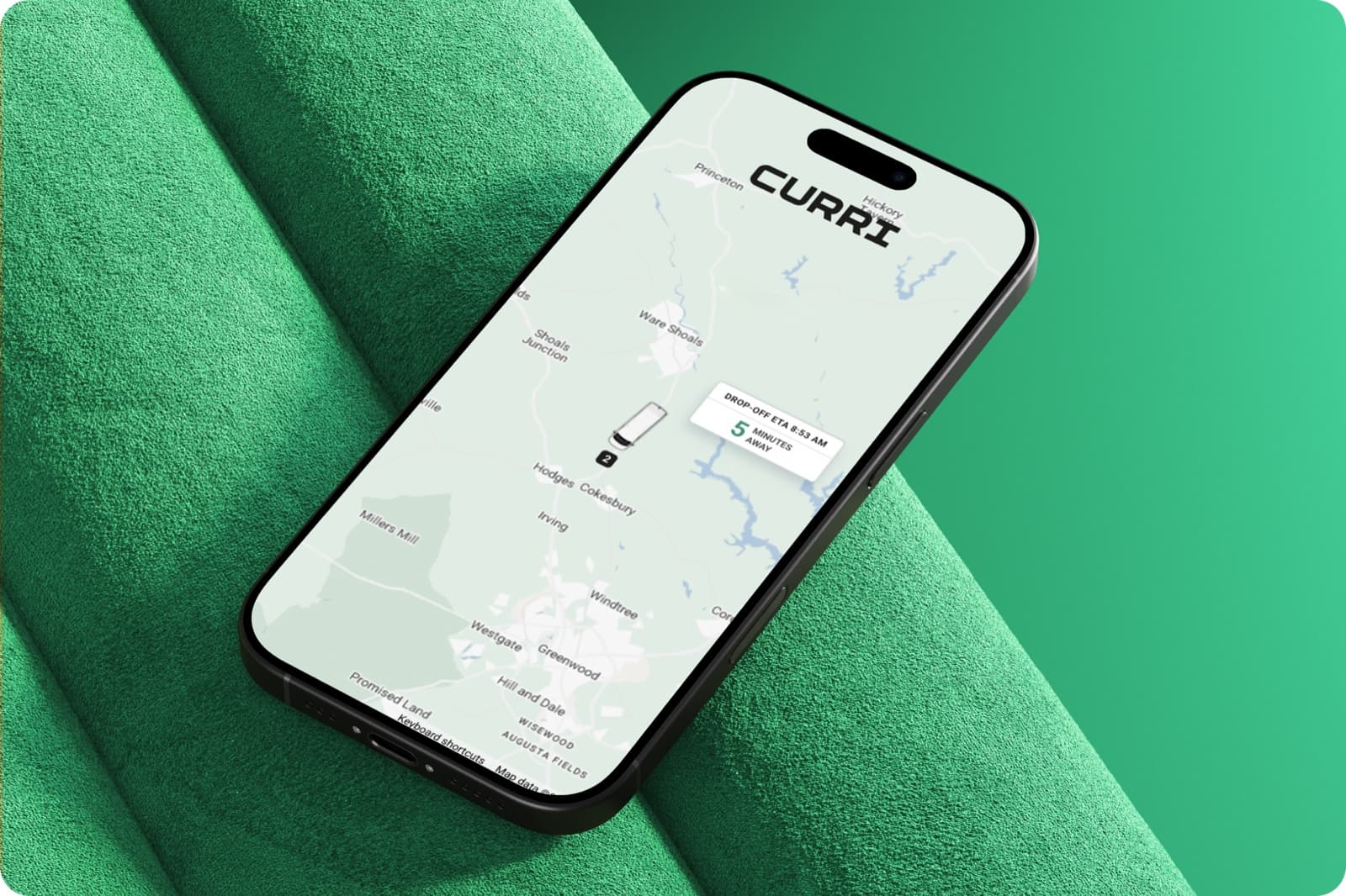 A smartphone showing the Curri app's live GPS tracking map with a drop-off ETA 5 minutes away, resting on a green surface.