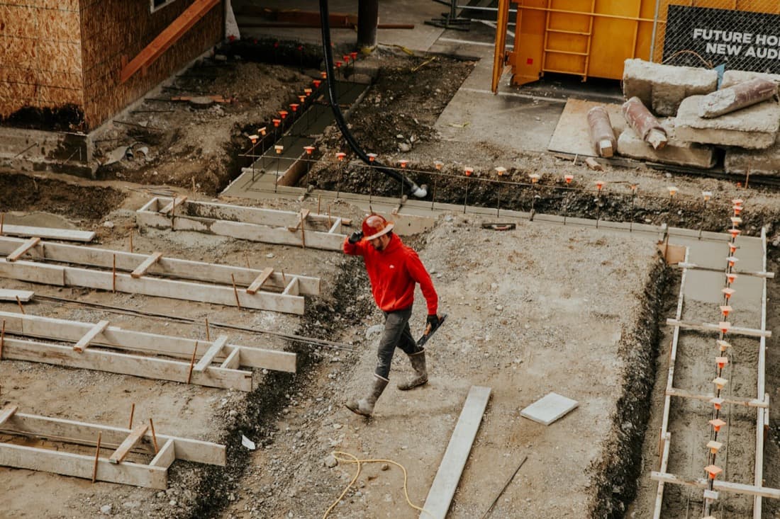 Curri carrier driver in a red jacket offloading construction materials at a jobsite — a branded delivery experience powered by Curri's third-party carrier network