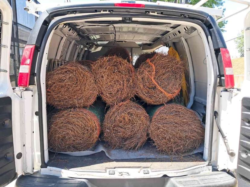 Cargo van rear loaded with bales of landscaping materials staged for a Curri jobsite delivery
