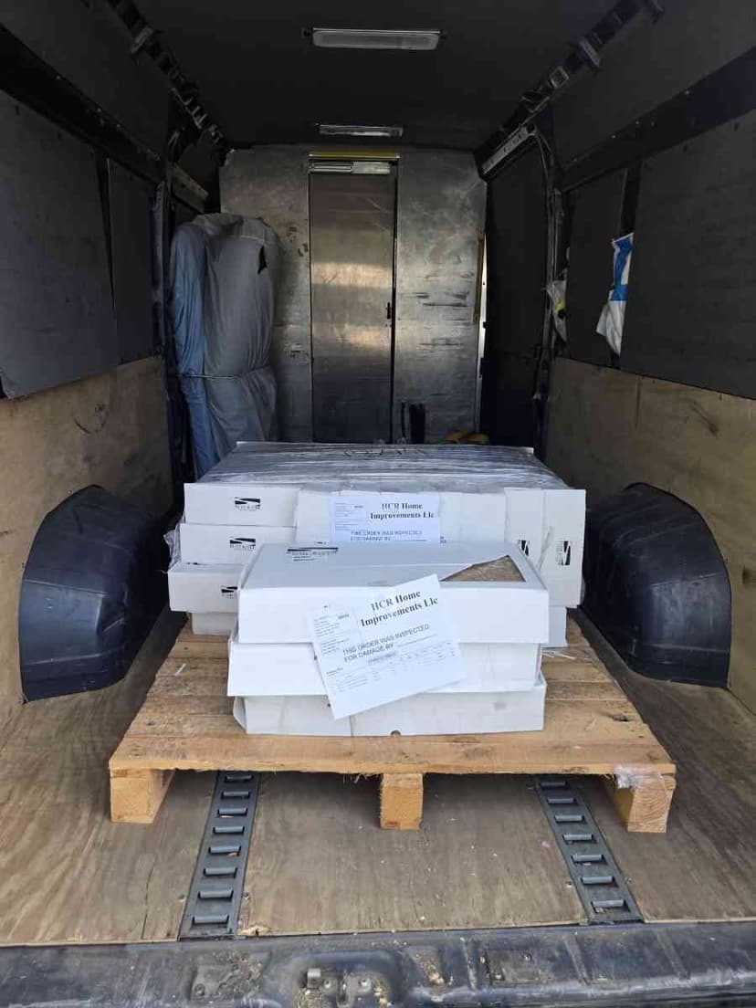 White cargo van parked at a lumber yard with side door open for a Curri building-materials pickup