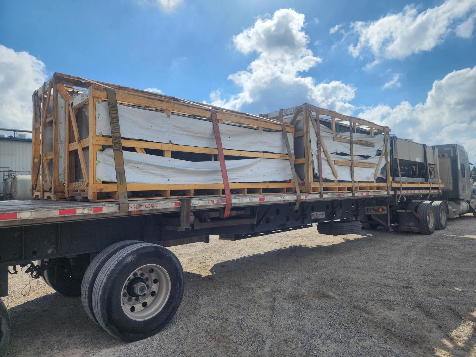 Curri flatbed semi-trailer loaded with strapped-down wood crates ready for a same-day heavy-freight delivery