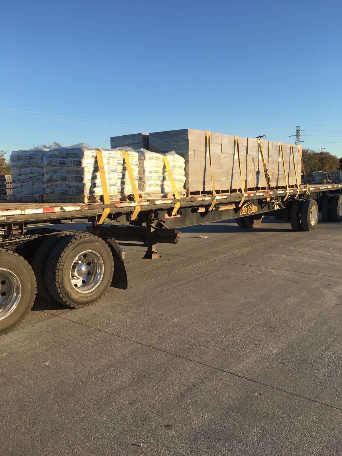Flatbed loaded with cement bags and lumber bundles strapped down for a Curri heavy building-materials haul