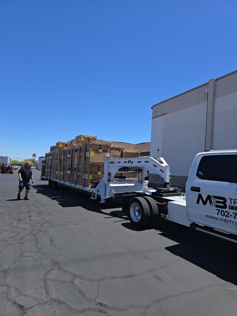 Gooseneck flatbed trailer behind a heavy-duty truck loaded with crated cargo for a Curri last-mile delivery