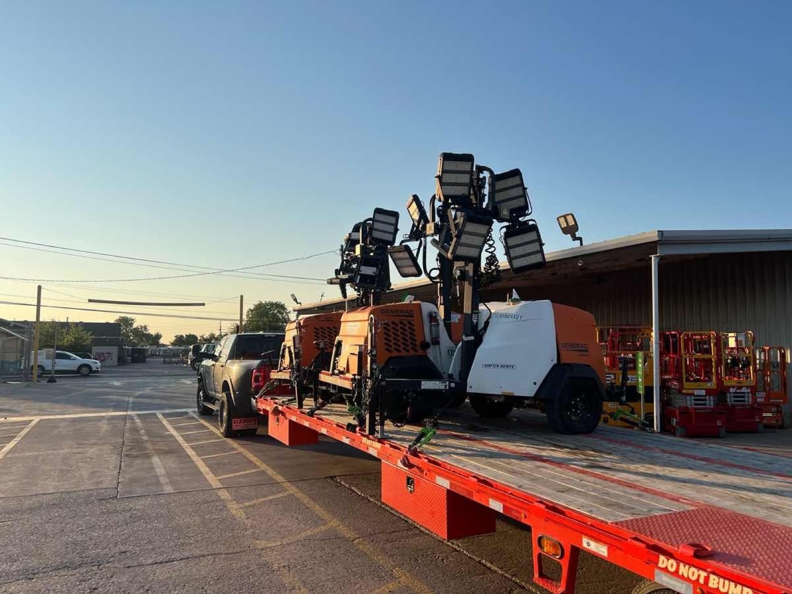 Flatbed hauling Generac light towers and rental equipment for a Curri jobsite drop-off