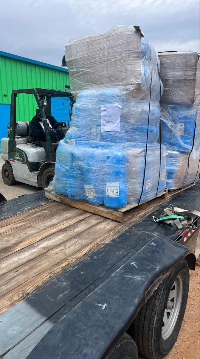 Forklift loading a shrink-wrapped pallet onto a Curri flatbed for a same-day Moffett-equipped delivery