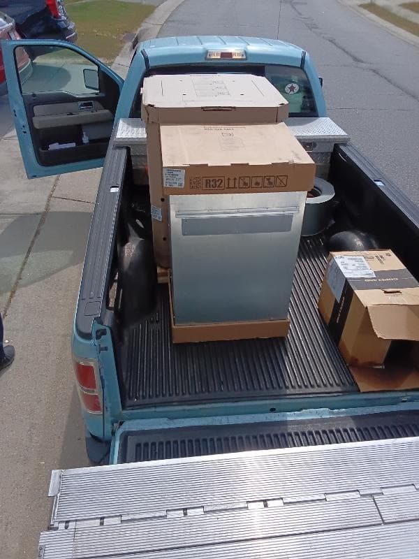 Teal pickup truck loaded with R32 refrigerant boxes and HVAC equipment for a Curri same-day supply run