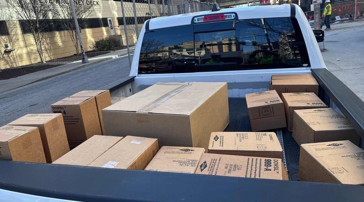 White pickup truck bed loaded with DOWSIL silicone boxes for a Curri construction-supply pickup