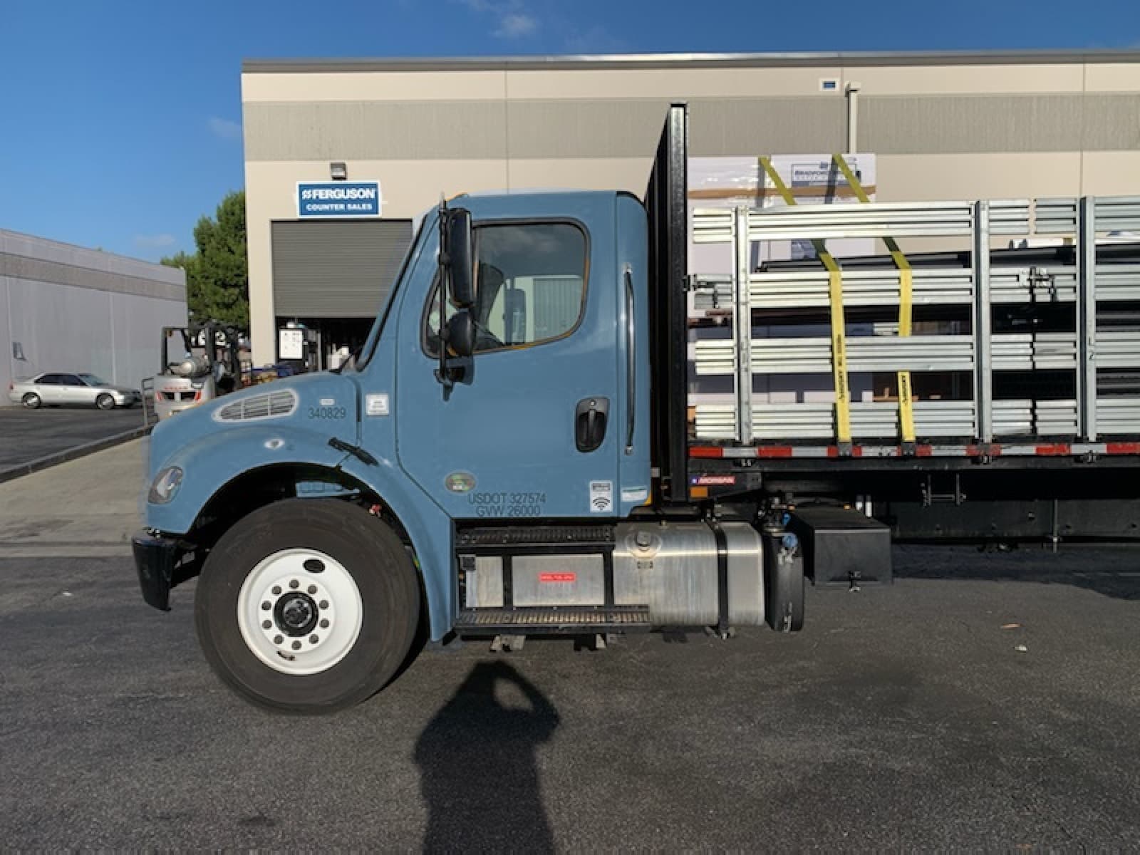 Light-blue Freightliner stakebed at a Ferguson counter-sales pickup for a Curri plumbing distributor delivery
