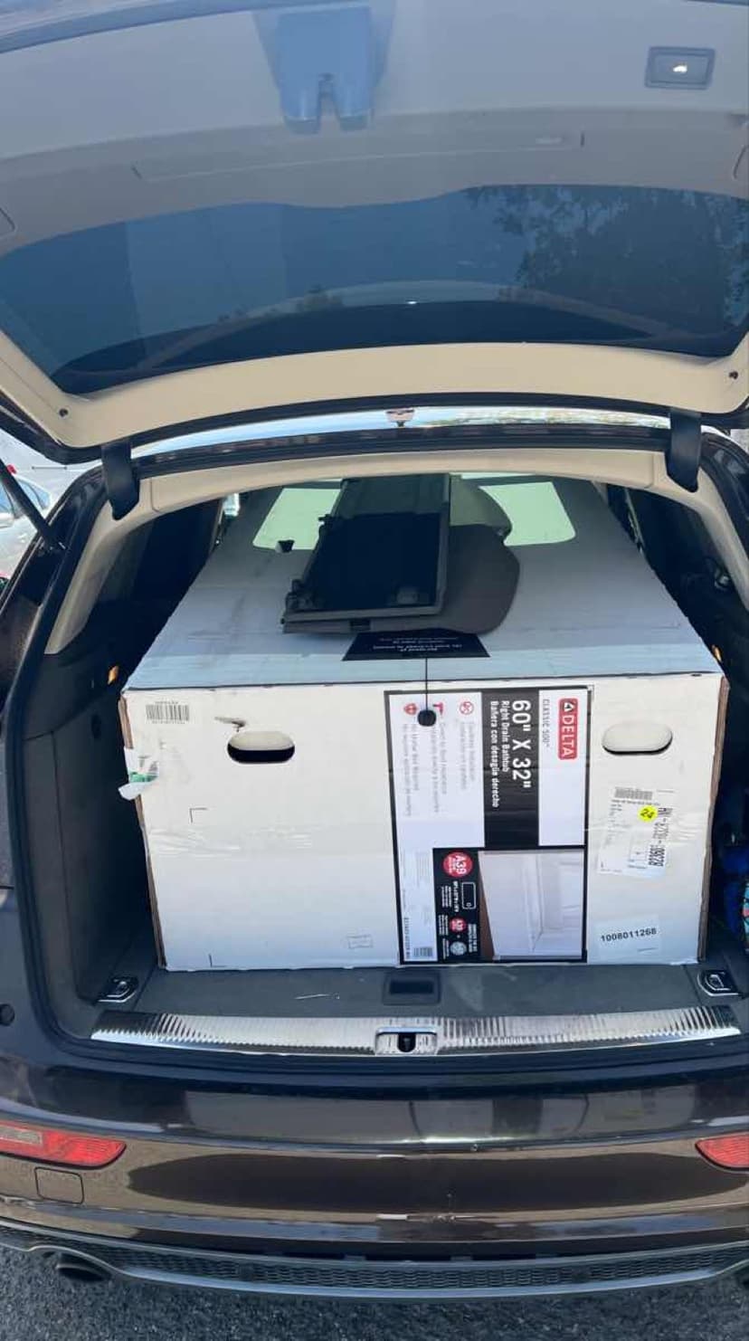SUV trunk loaded with a large white Delta tub box ready for a Curri kitchen and bath delivery