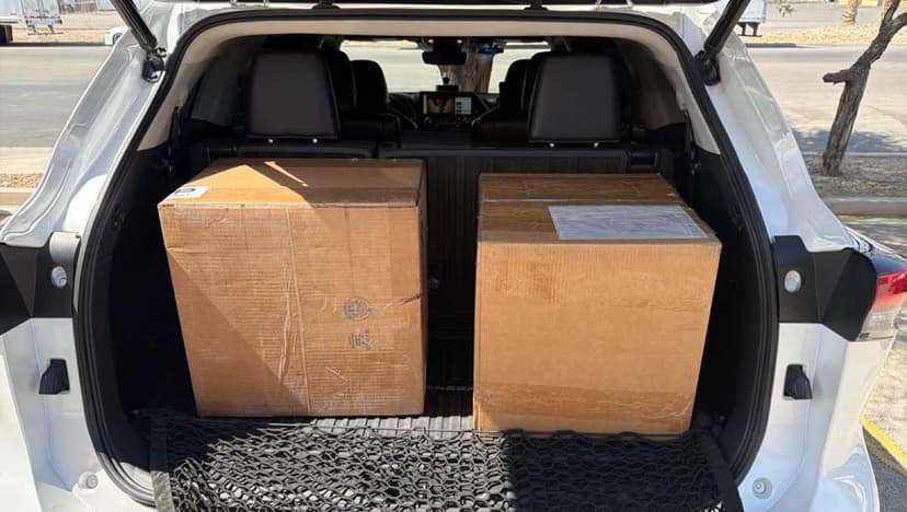 White SUV cargo area with two large cardboard boxes staged for a Curri same-day local delivery