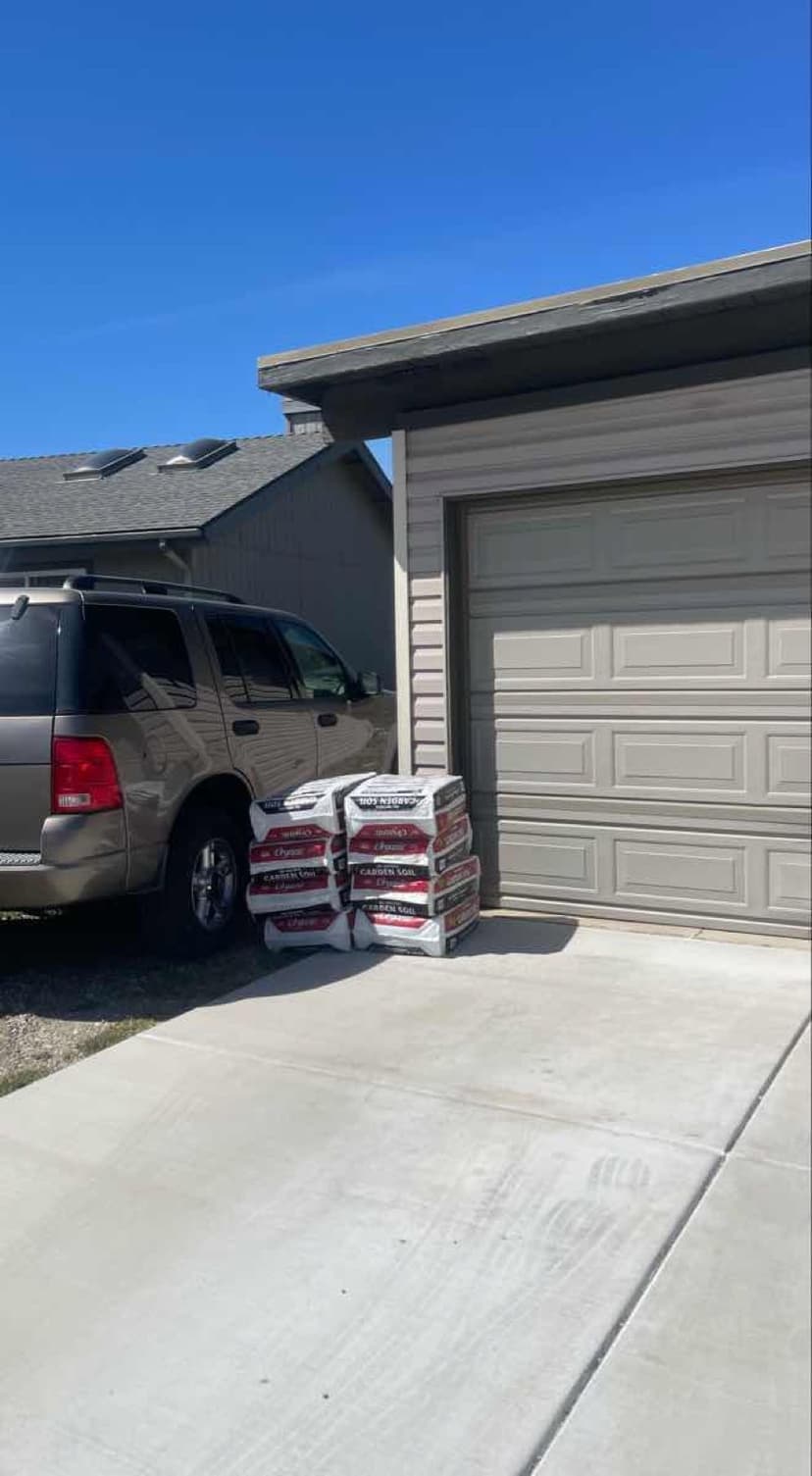Tan Ford Explorer SUV loaded with stacked Sherwin-Williams garden soil bags for a Curri landscaping delivery