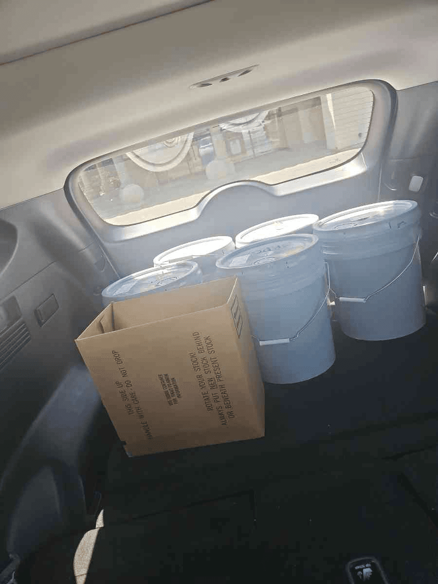 SUV interior loaded with paint pails and a parts box for a Curri trade-supply route