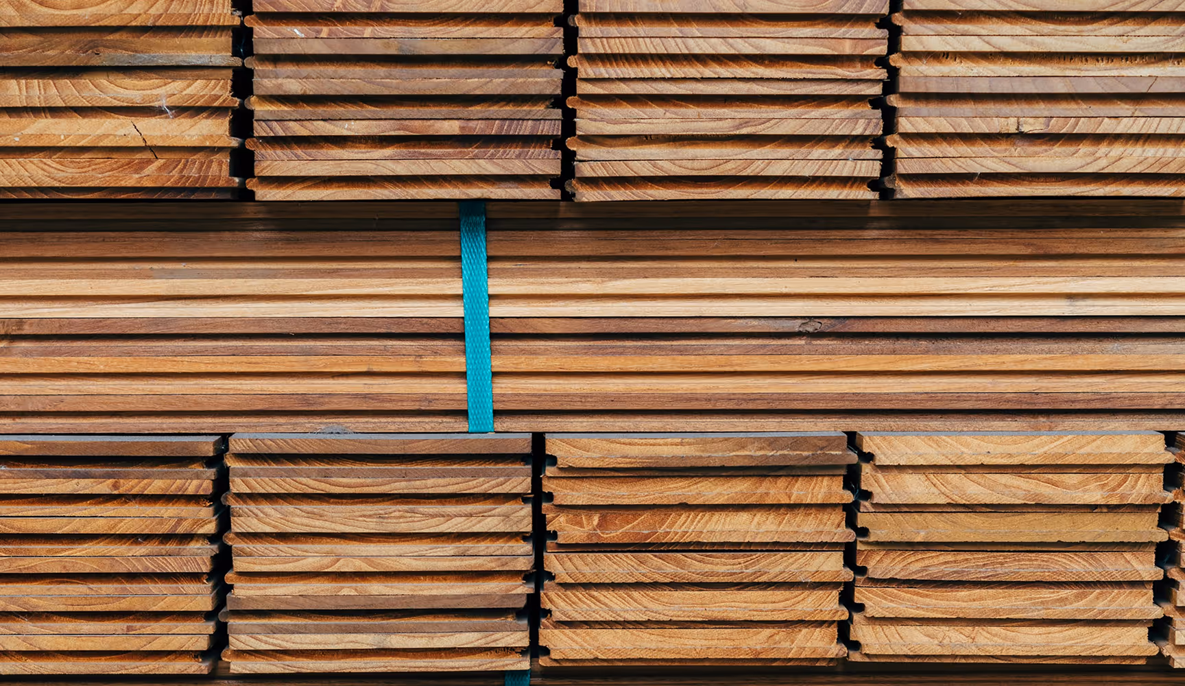 Stacked bundles of hardwood flooring planks banded with a green strap sit ready to ship—the kind of LVP, hardwood, and laminate inventory Curri's fleet moves from suppliers to installers same-day.