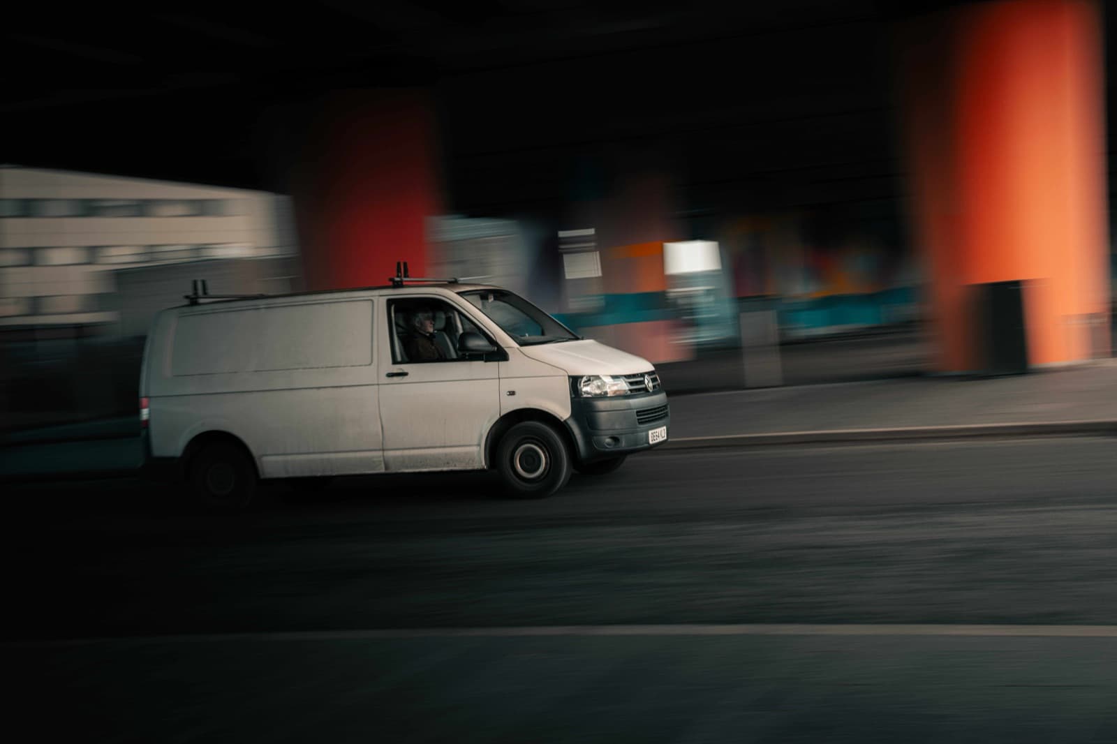 White cargo van speeds through a dim urban underpass in motion blur, powering the kind of same-day, buy-online-deliver-from-store last-mile retail delivery Curri runs nationwide.