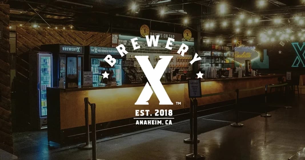 The bar at Brewery X in Anaheim under strings of lights, with the Brewery X mark over it