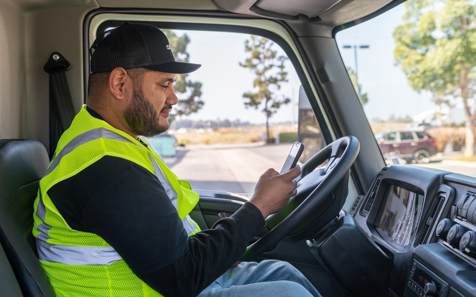 Image of a delivery driver sitting inside their vehicle and confirming delivery details on phone